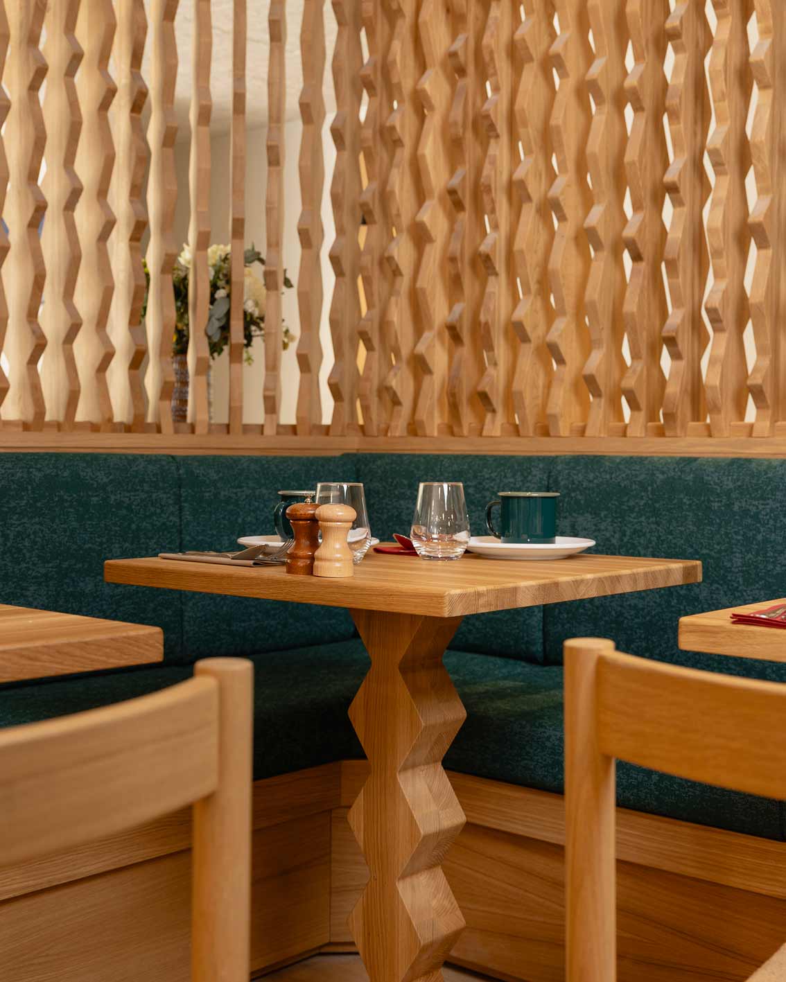 Espace restaurant & PDJ de l'hôtel la Couronne à Chamonix74. Le mobilier est en bois et le piétement de table a des motifs géométriques que l'on retrouve sur la cloison bois ajourée pour une ambiance chaleureuse