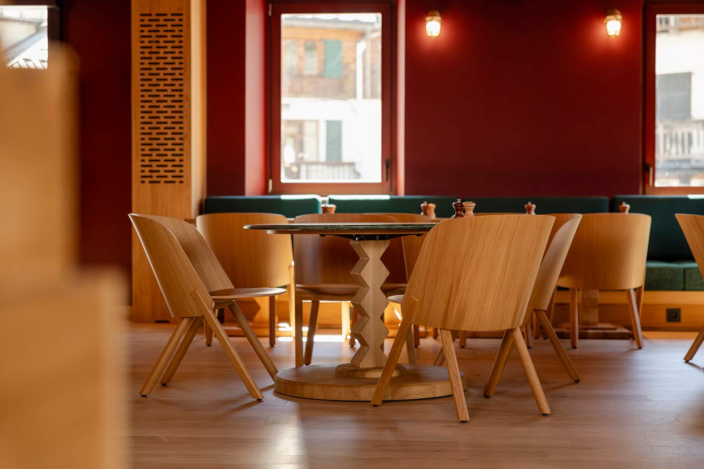 Restaurant de l'hôtel la Couronne à Chamonix74. les chaises et les tables sont en bois. Les tables ont un piétement géométriques dans un style de montagne. Pour compléter le côté chaleureux, les murs et le plafond sont rouges